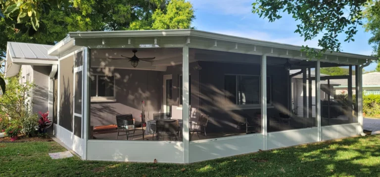 How can I pay for my patio cover installation? 6 A modern screened-in patio with a metal roof, featuring several black chairs and a small table, surrounded by green grass and trees.
